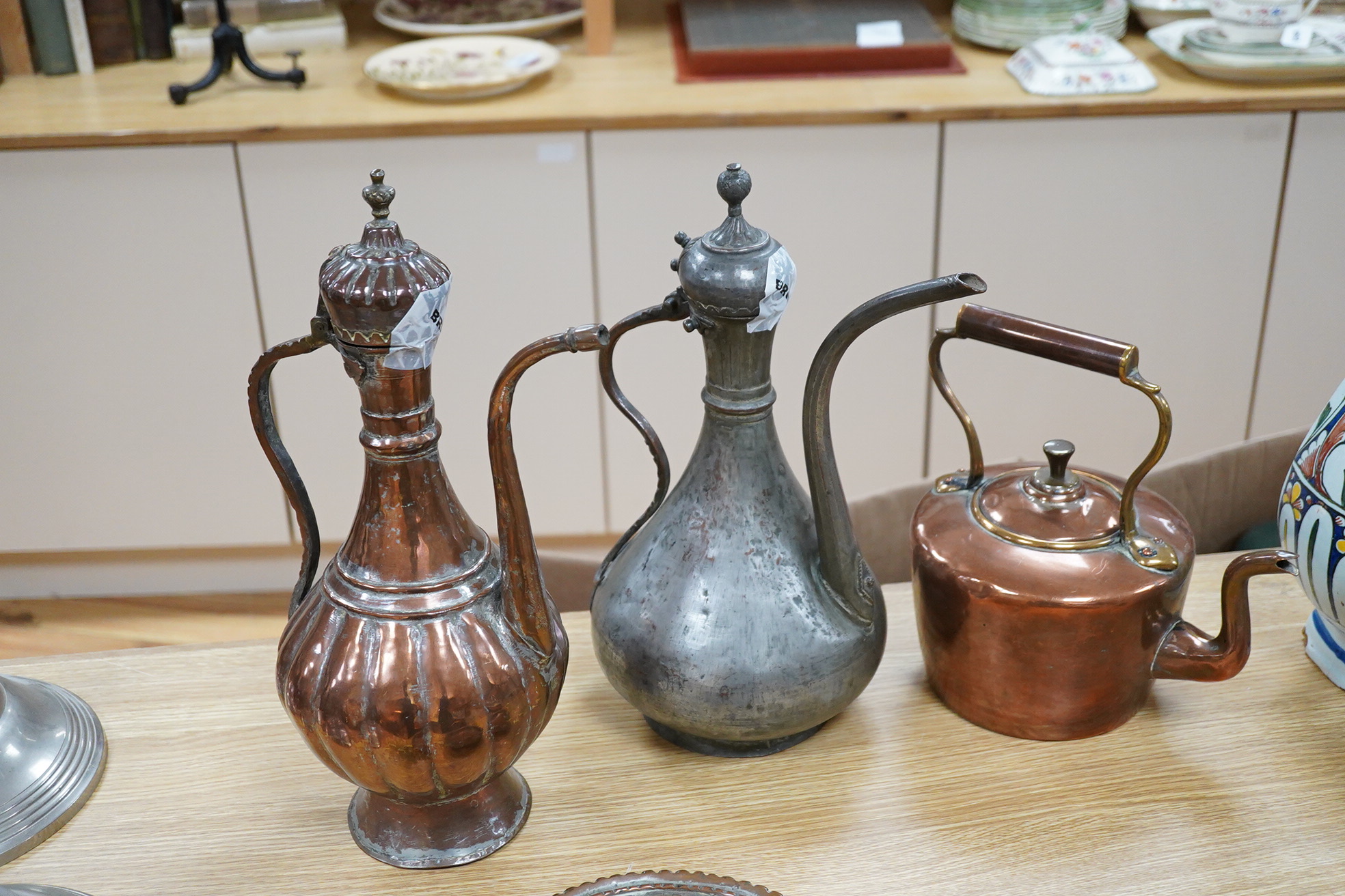 Two Middle eastern tinned copper coffee pots ‘Dallah’ a similar dish and a European copper kettle, tallest 41cm high